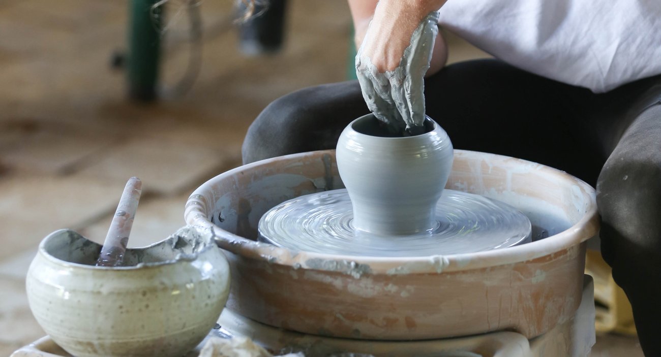 A person forms a vase on a pottery wheel