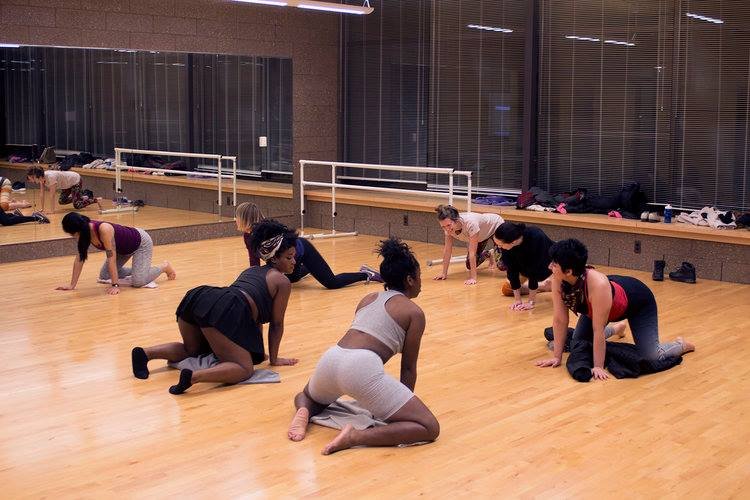 A group of people in a dance studio on their knees learning the fundamentals of twerking.