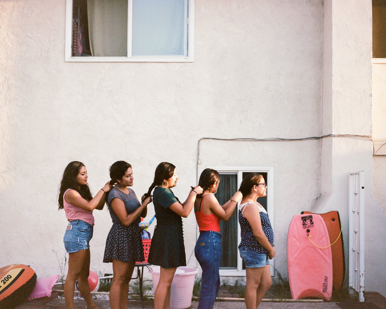 Image of a line of girls braiding each other’s hair.