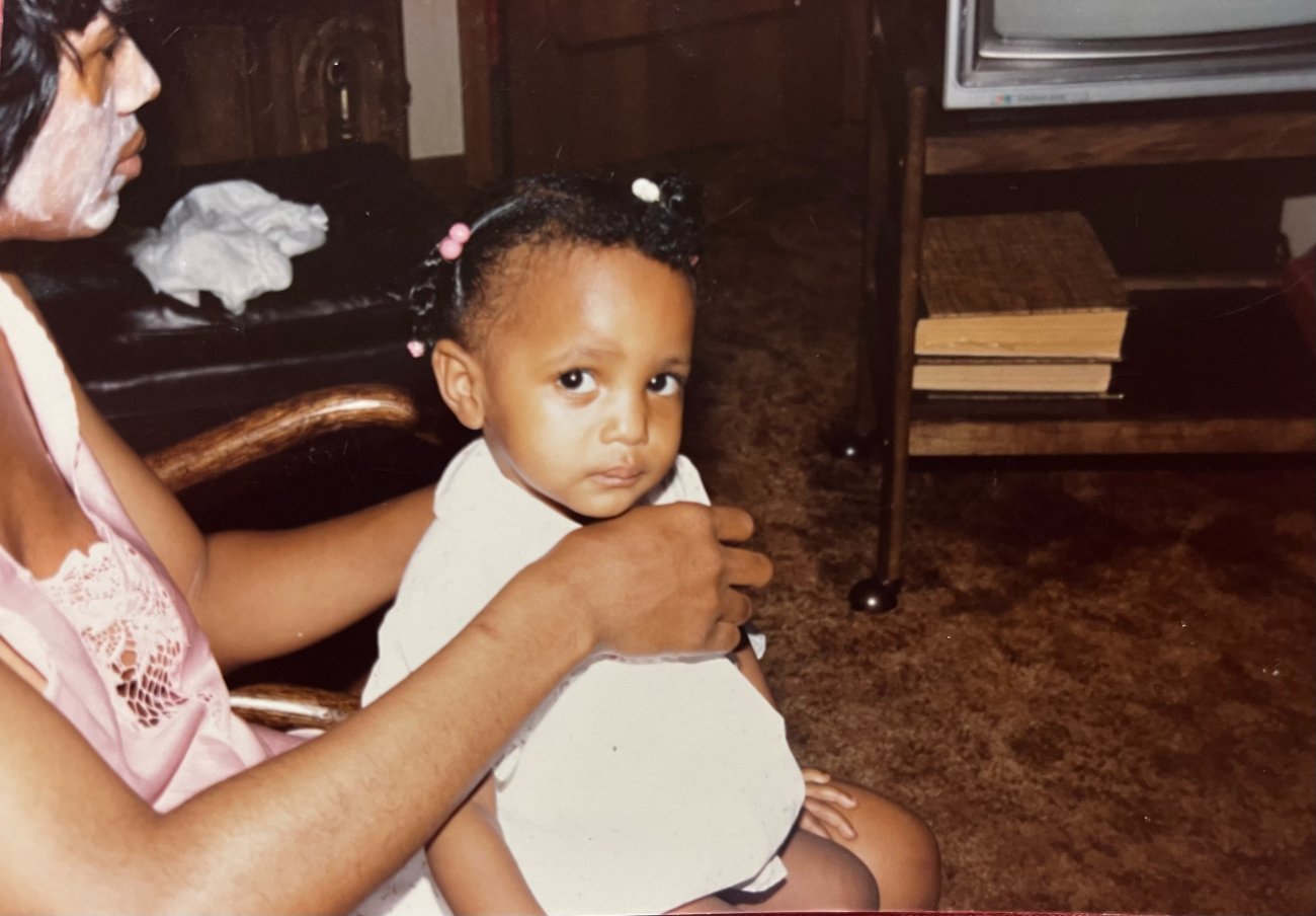Family photo of Fatima Laster sitting on someone's lap, looking into the camera.