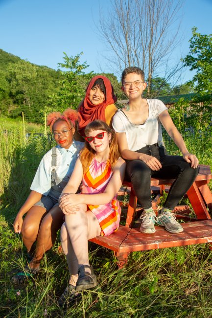 Artists seated at red picnic table at sunset