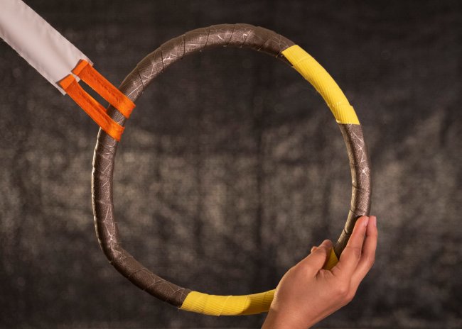 Photograph of hand holding a circular object against a grey background