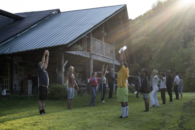 Artists lined up facing each other in front of the lodge doing workshop exercise