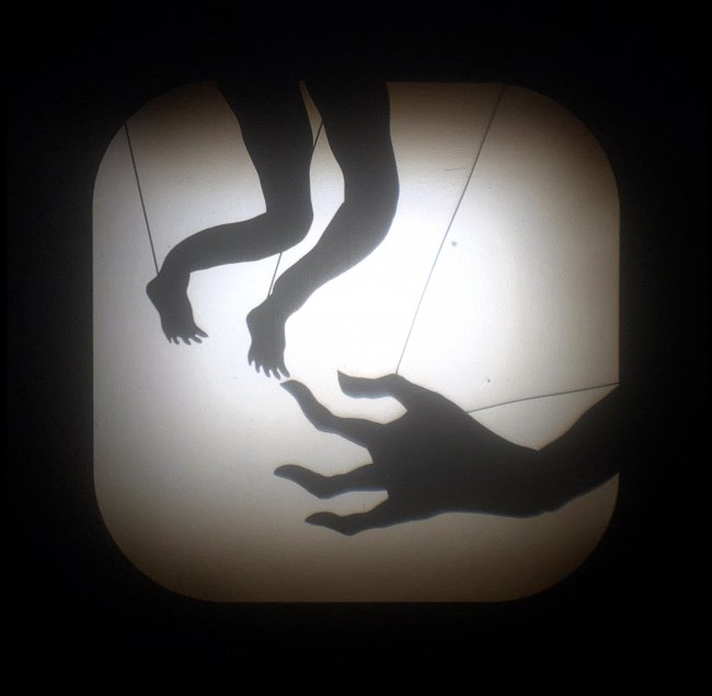 A still image of Johanna Winter's shadow puppet piece, "Untouching" featuring a silhouette of a hand reaching to a silhouette of two small feet